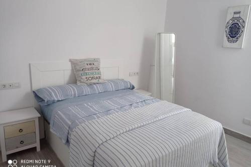 特吉塞Precioso apartamento con terraza en Teguise的白色卧室,配有带条纹毯子的床