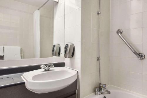 韦斯特勒姆Days Inn by Wyndham Sevenoaks Clacket Lane的白色的浴室设有水槽和淋浴。