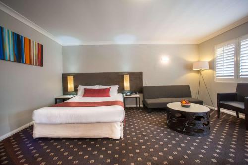 CabramattaRamada Hotel & Suites by Wyndham Cabramatta的酒店客房设有一张大床和一张沙发。