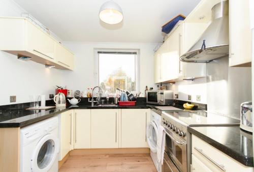 阿伯丁Aberdeen Quiet City Apartment, Ferryhill的厨房配有白色橱柜、洗衣机和烘干机
