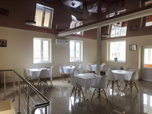 哈尔科夫Bloom Hotel的一间设有白色桌椅和窗户的用餐室