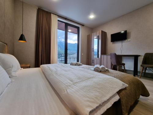 卡兹贝吉Hotel Olympus Kazbegi的一间卧室设有一张大床和大窗户