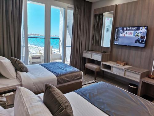 马特鲁港Jewel Beach Matrouh Hotel的酒店客房设有两张床和一台平面电视。