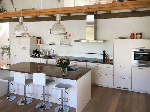 KapelleHoliday Home De Meestoof by Interhome的一间厨房,配有白色橱柜和一个带酒吧凳的岛屿