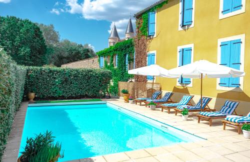 比兹米内瓦Logis hôtel et restaurant La Bastide Cabezac的一座带椅子和遮阳伞的游泳池位于一座建筑旁边