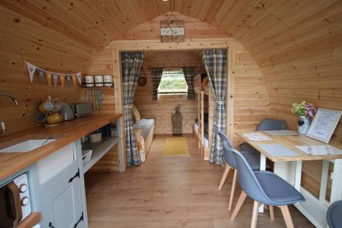 多尔盖罗Glamping Huts in Heart of Snowdonia的小木屋的厨房和用餐室配有桌椅