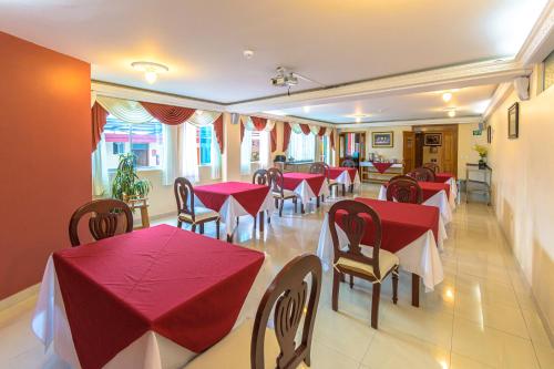 基多Hotel Cumbayá Sanvy的餐厅设有红色的桌椅和窗户。