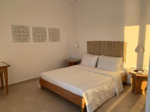米克诺斯城BAY VIEW RESIDENCE的一间卧室配有一张带白色床单的床和两张桌子