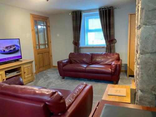 因弗内斯No 10 The Cottage的客厅配有真皮沙发和平面电视