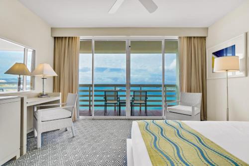 法哈多El Conquistador Resort - Puerto Rico的酒店客房设有一张床和一张书桌,享有美景。
