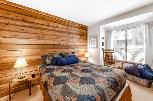 LakeshoreHuntington Lake Condo 92的一间卧室设有木墙和一张床
