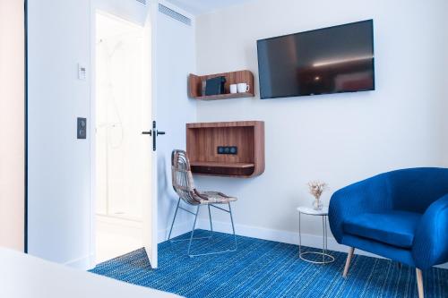巴黎Hôtel Bleu de Grenelle的一间设有蓝色椅子和电视的房间