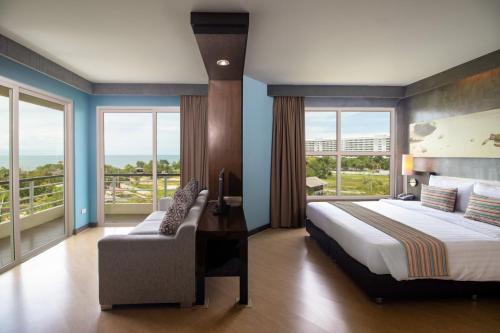 华欣Sila at Hua Hin Serviced Apartment & Hotel的一间卧室配有一张床、一张沙发和窗户。