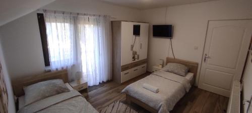 奥托查茨Apartman Majetić的一间卧室设有两张床、一台电视和一扇窗户。