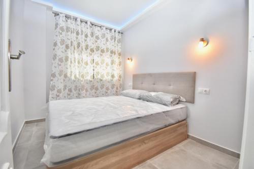福恩吉罗拉Luxury Suites Fuengirola的一张小床,位于带窗帘的房间