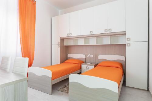 卡布拉斯CASA L'ANGOLO FIORITO的配有白色橱柜和橙色床单的客房内的两张床