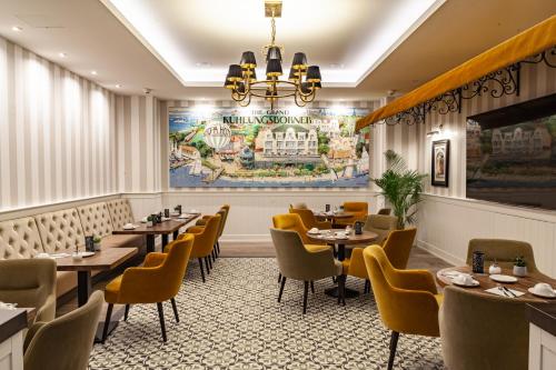 奥斯赛拜-屈隆斯博恩欧罗巴库兰斯伯恩酒店的餐厅设有桌椅,墙上挂有绘画作品