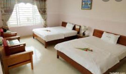 岘港NHÀ NGHỈ MINH NHI的酒店客房设有两张床和窗户。