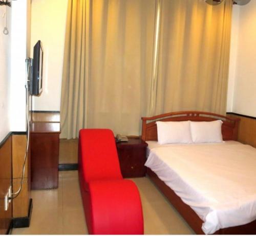 岘港NHÀ NGHỈ MINH NHI的酒店客房,配有一张床和一张红色椅子