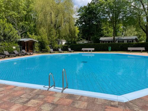 博克斯特尔Gasterij Hotel Dennenoord的一个带椅子和树木的大型蓝色游泳池