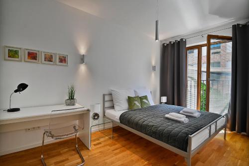 克拉科夫Apartamenty Prestige Browar Lubicz Stare Miasto的一间卧室配有一张带书桌的床和窗户。
