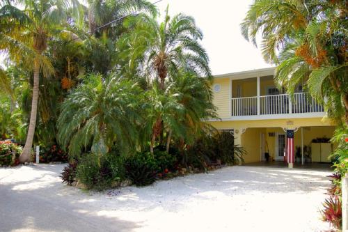 萨拉索塔Siesta Palms By the Beach的棕榈树前方的黄色房子