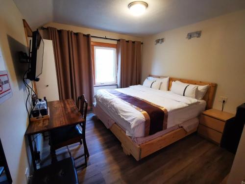 班夫Riverfront Estate Bed&Breakfast Banff的一间卧室配有一张床、一张书桌和一个窗户。