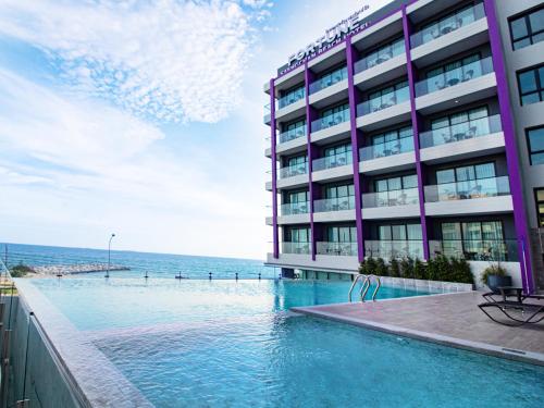 罗勇Fortune Saeng Chan Beach Hotel Rayong - SHA Plus的毗邻大海的带游泳池的酒店