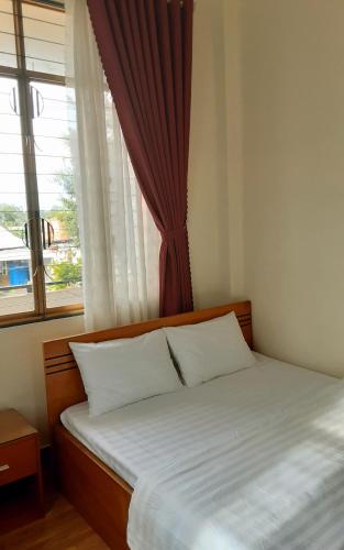Giồng Tú ÐiềnQue Huong Coconut Hotel的窗户和床筒的床上床