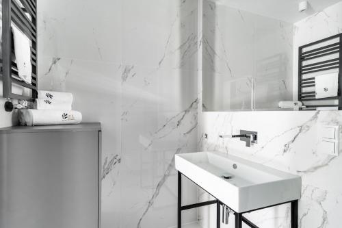 波兹南EL Apartments - Hercules的白色的浴室设有水槽和大理石墙壁。