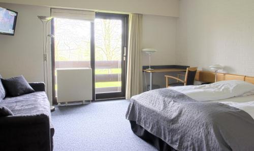 Hovborg霍夫伯格克罗酒店的一间卧室配有一张床、一张沙发和一个窗口