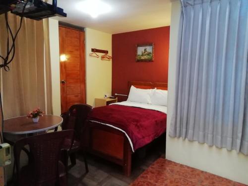 胡利亚卡Hostal Sumak'usi的酒店客房配有一张床铺和一张桌子。