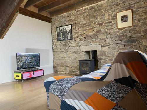 LannédernLes Chambres De Napoleon的一间卧室设有石墙、一张床和电视。