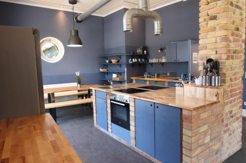 罗斯托克Blue Doors Hostel KTV的厨房配有蓝色橱柜和砖墙