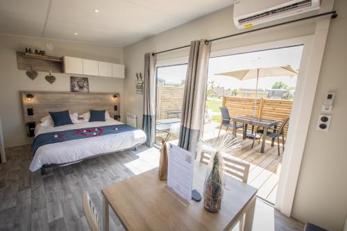 Langrune-sur-MerM&V Resort Camping的一间卧室配有一张床,庭院配有桌子