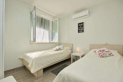 ProžuraSTIGA 2 - two bedroom ap.的白色的客房设有两张床和窗户。