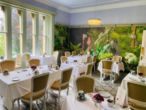 杜伦法恩利塔旅馆的一间设有白色桌椅的餐厅,种植了植物