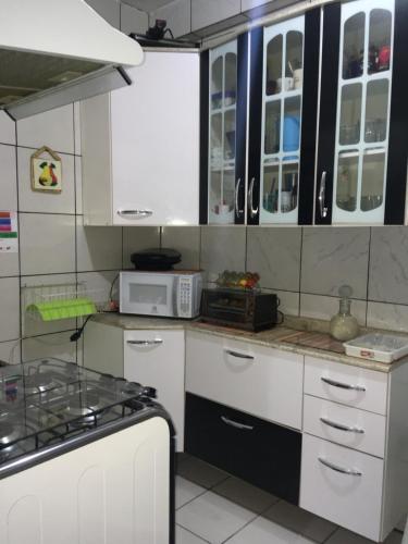奥萨斯库Quarto INDIVIDUAL Casa Super Aconchegante WIFI 350 MEGA的厨房配有白色橱柜和炉灶烤箱。