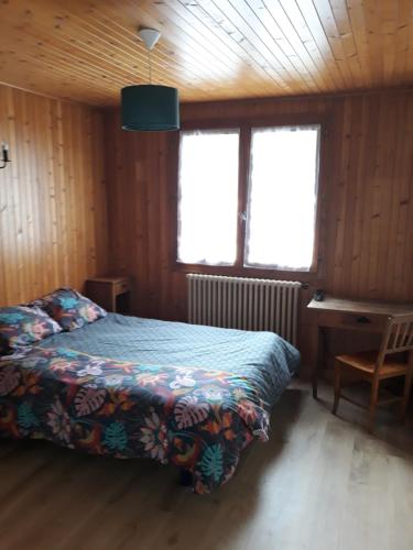 拉克吕萨Les Granges的一间卧室配有一张床、一张书桌和两个窗户。