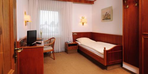 金斯海姆-古斯塔夫斯堡阿尔特波斯特卡尼酒店的一间卧室配有一张床和一张书桌及电视