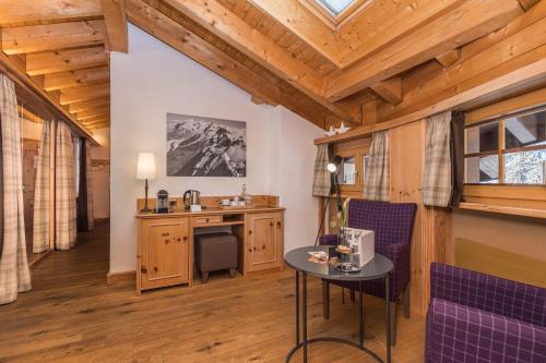 采尔马特Hotel Bella Vista Zermatt的客房设有梳妆台和带紫色椅子的桌子。