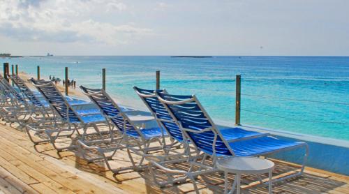 Creek VillageDeluxe Sea View Villas at Paradise Island Beach Club Resort的海滩上一排蓝色椅子