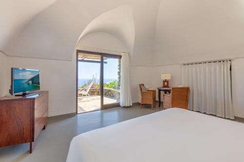 潘泰莱里亚Pantelleria Dream Resort的一间卧室配有一张床和一张书桌及电视