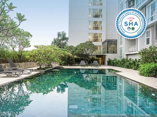 Si Maha Phot304花园酒店的一座游泳池,在一座建筑前有标志