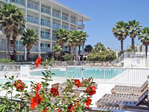 巴拿马城海滩Boardwalk Beach Hotel的一座拥有游泳池、棕榈树和鲜花的酒店