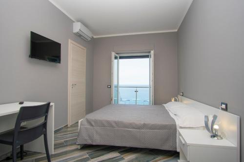 卡梅罗塔码头La Dimora sul Mare的一间卧室配有一张床、一张书桌和一个窗户。