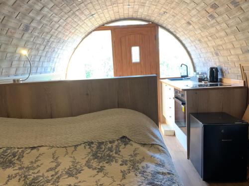 希尔内斯Romantic escape luxury Hobbit house with Hot tub!的一间卧室配有一张床,厨房配有窗户