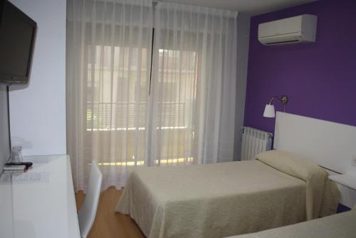 格拉纳达Verona的酒店客房,设有床和带窗帘的窗户。