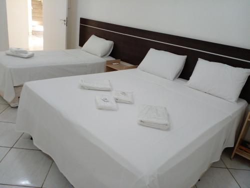 蒙蒂斯克拉鲁斯Hotel Minas Brasil的一间卧室配有两张带白色床单的床