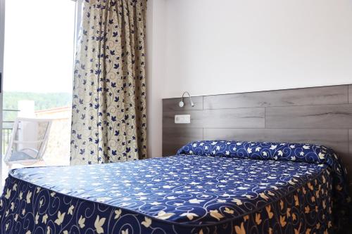 蒙塔尼约斯肖恩酒店的一间卧室配有一张带蓝色棉被的床和窗户。